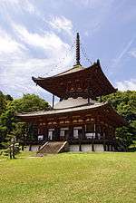 A large two-storied pagoda shaped tower with a square base and a round upper story. The walls are white and the beams faded red.