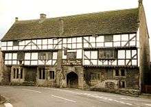 White fronted building with black beams prominent. Over the door is a sign saying The George Inn, Wadworths.