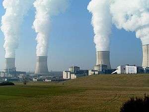 Nuclear power plant in Cattenom, France four large cooling towers expelling white water vapor against a blue sky