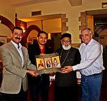 Four men holding an icon of three saints