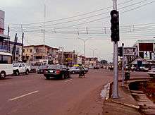 A picture of Ogui Road in Enugu with a traffic light to the right and the rest of the street heading straight down with shops and businesses on the street side