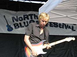 Paul Nelson on stage, playing an electric guitar