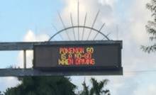 A variable-message sign over a road that reads "Pokémon Go is a no-go when driving".