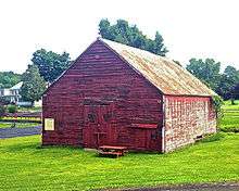 A view showing the front and the other side of the building. It has less paint but is in better condition than the side shown at the top of the page