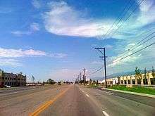 A 5 line asphalt roadway and blue skies and some white clouds