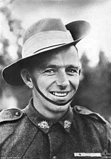 A head and shoulders portrait of a smiling man in military uniform.