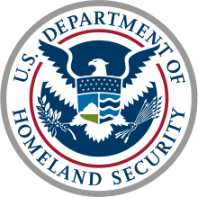 A graphically styled American eagle appears in a circular blue field. The eagle's outstretched wings break through an inner red ring into an outer white ring that contains a circular placement of the words "U.S. DEPARTMENT OF" in the top half and "HOMELAND SECURITY" in the bottom half. The outer white ring has a silvery gray border. As in The Great Seal, the eagle’s left claw holds an olive branch with 13 leaves and 13 seeds while the right claw grasps 13 arrows. Centered on the eagle's breast is a shield divided into three sections containing elements that represent the homeland "from sea to shining sea." The top element, a dark blue sky, contains 22 stars representing the original 22 agencies and bureaus that have come together to form the department. The left shield element contains white mountains behind a green plain underneath a light blue sky. The right shield element contains four wave shapes representing the oceans, lakes and waterways alternating light and dark blue separated by white lines.