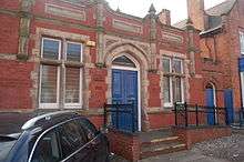 A blue-painted wooden door in a Victorian redbrick wall