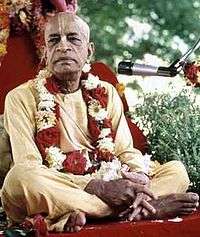 An Indian swami sitting on a chair closs-legged