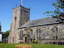 A stone church seen from the south-east with a square, battlemented tower to the left, and the body of the church extending to the right.