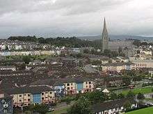 A view of Derry looking towards St Eugene's Cathedral, the mother church of the Roman Catholic diocese of Derry, across the Bogside's Lackey Road and Fahan Street, taken from the Grand Parade on the City Walls. Houses are visible, two have a mural