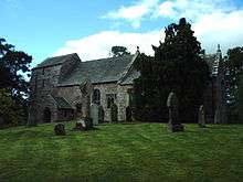 A stone church seen from the southeast with an elongated squat west tower surmounted by a saddleback roof