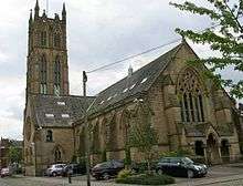 A stone church from the southeast with a south transept and a pinnacled tower