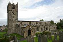 A stone church see from the south with a slim west tower, a battlemented south aisle, and a clerestory with three-light windows