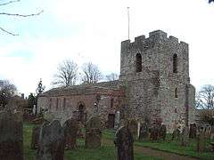 A stone church seen from the northwest with a squat west tower and a north aisle containing thin lancet windows