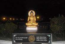 Gold-coloured, seated Buddha statue on a pedestal