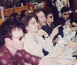 Five men sitting at a table at a press conference