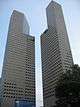 Ground-level view of two identical 45-storey towers with rectangular cross sections; a diagonal cut-out is present on each tower near the 30th floor