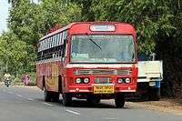 A bus in a road with tress in the background