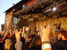 Turunen with her support band in front of a crowd at the Wacken Open Air.