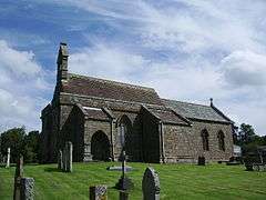 A stone church seen from the southwest with a west bellcote