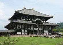 Huge wooden building with white walls and dark beams.