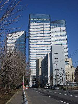 Ground-level view of a three-building complex; each building is white and blue and lined with rows of windows