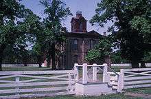 Historic brick courthouse behind a white fence.