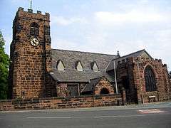 A Gothic style sandstone church with a grey slate roof seen from the south; a crenellated tower to the left, a porch in the middle and a large chapel projecting on the right