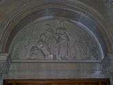  Carved stone tympanum showing mill workers at the loom with a sheet of finished cloth