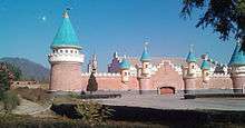 A grey concrete and brick castle, wood frames outlining the conical roofs