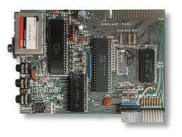 Top-down view of the ZX81 motherboard showing the layout of the components. Four chips are prominent, along with a TV modulator on the top left and a ribbon cable on the bottom right.